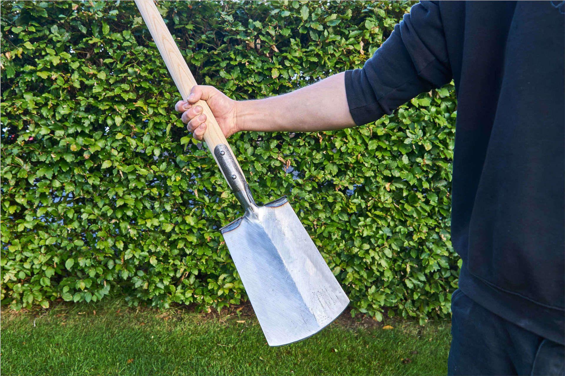 Ein geschmiedeter Spaten in den Händen eines Mannes im Garten von der Manufaktur Baack Spaten
